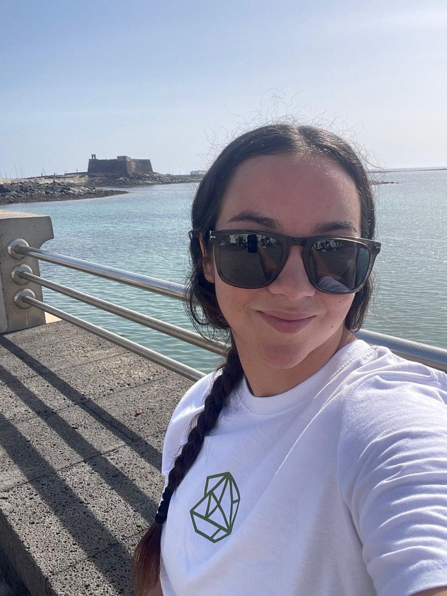 Ayshane Mederos con gafas de sol en el paseo marítimo de Arrecife, con el castillo de San Gabriel al fondo